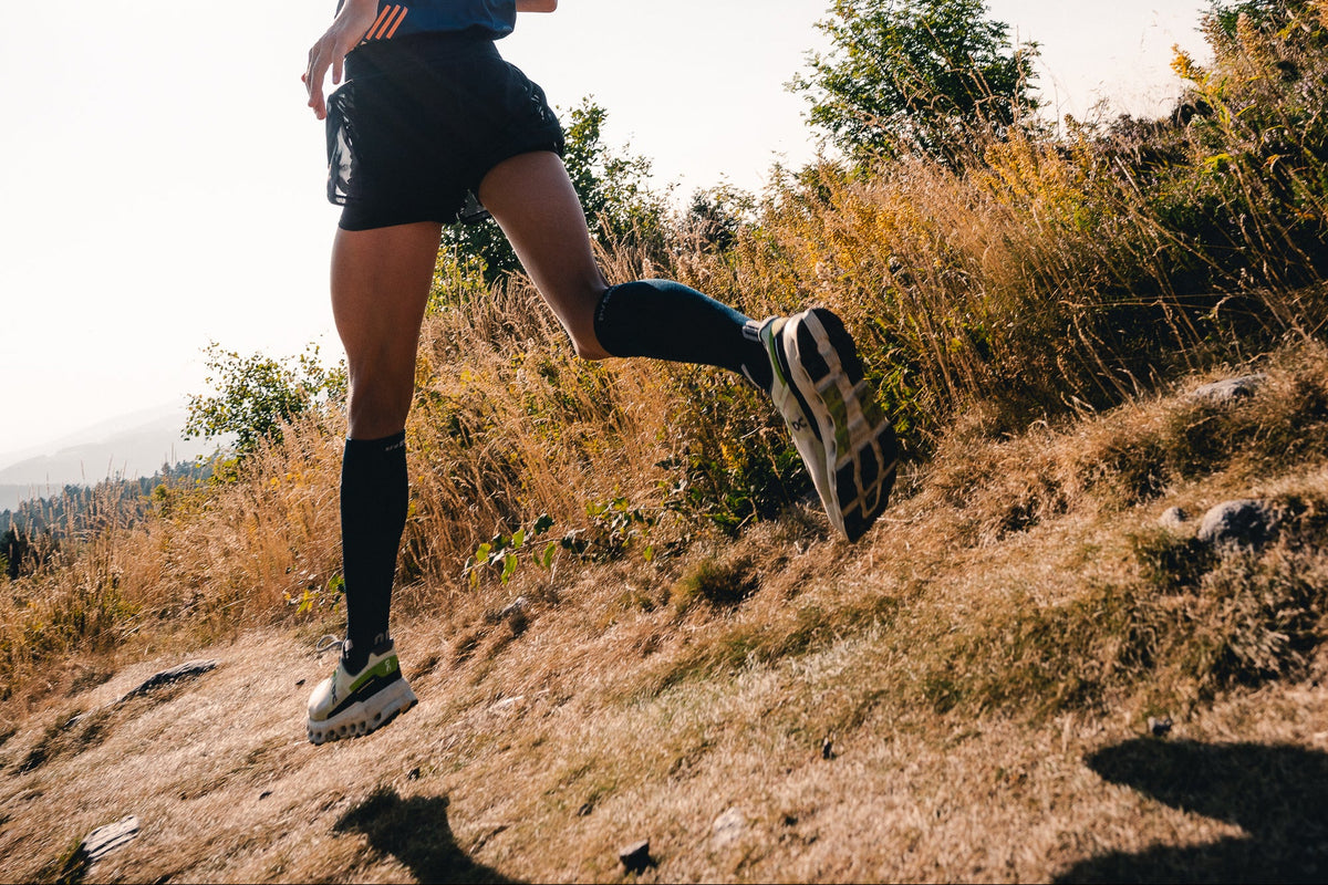 Person running on a trail with a clear blue sky
